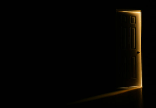 Puerta entreabierta en una habitación oscura con luz que entra, como invitación a conversar
